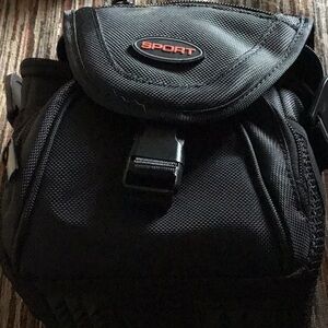 Black sport camera bag with no strap 5 inches tall a lot of compartments